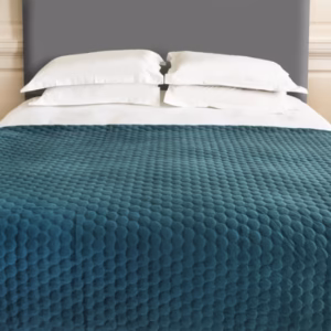 Teal Halo throw styled across a bed with quilted geometric texture